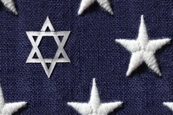 White Star of David emrboidered on navy cloth alongside five pointed stars as if depicting an altered version of the American flag
