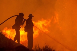 Silhouette of firefighters facing a blaze