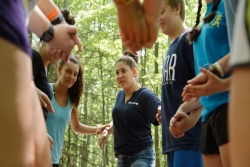 Group of teen campers holding hands in a circle as if participating in a group activity