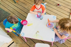 Three small children eating homemade ice cream at a picnic table 
