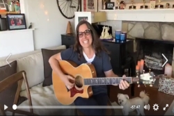 Screenshot of a video of Jewish musician Julie Silver smiling with a guitar