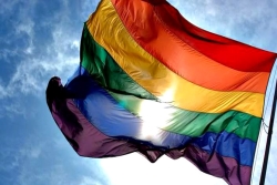 LGBT rainbow flag blowing against a blue sky