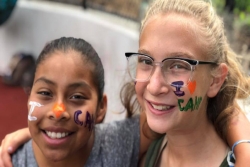 Two smiling tween girls with I LOVE CAMP written on their cheeks in face paint