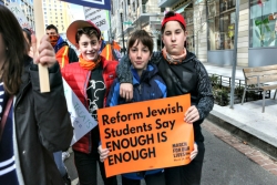 Three teen boys holding signs that read REFORM JEWISH STUDENTS SAY ENOUGH IS ENOUGH