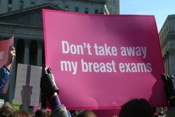 Pink sign saying "Don't take away my breast cancer screenings" at rally 