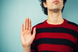 Closeup of a man in a striped sweater with his hand up by his side as if pledging or making a promise 