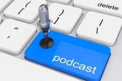 Computer keyboard; the return key is blue and says podcast; a small microphone sits on the blue key