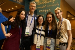 Rabbi Rick Jacobs poses with three smiling teens in NFTY Convention badges