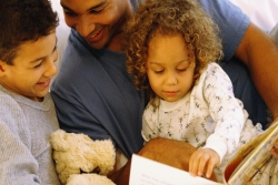 Father reading a book with his young son and daughter