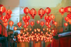 Red paper lanterns hanging over a street at twilight