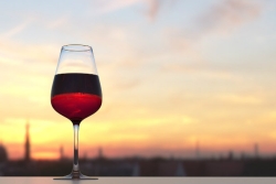 Full glass of red wine sitting on a table in front of a sunset
