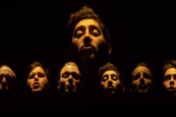 Screencap from Six13 video of its members faces illuminated against a black background