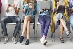 Row of young people on various personal electronic devices