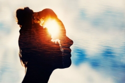 Creative concept image of a woman profile with a bright sunset appearing as though its inside her head