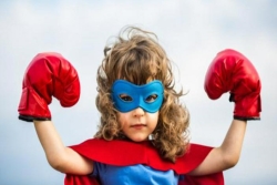 Little girl wearing a superhero mask and boxing gloves 