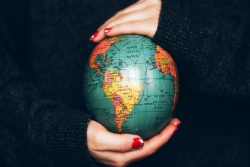 Womans hands with red painted fingernails holding a small globe replica 