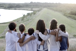 Campers dressed in Shabbat whites with their arms around one another as they face a nature scene