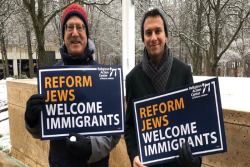 Two men holding signs that say "Reform Jews Welcome Immigrants"
