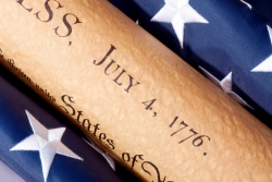 Declaration of Independence rolled up between two rolled up American flags