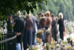 Group of people gathered at a gravesite in a cemetery