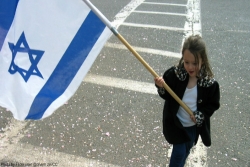 Young girl waving large Israeli flad on a pole
