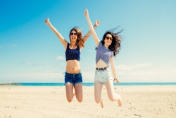 Two girls jumping in the air on the beach