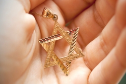Gold star of David necklace in palm of hand
