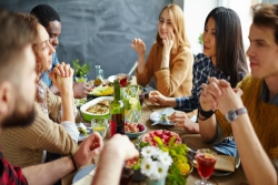 Group of people sitting around a dinner table enjoying food and company