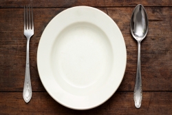 Empty plate on a table with fork and knife on either side 