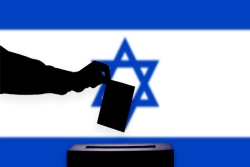 Silhouette of a hand dropping a ballot into a ballot box in front of an Israeli flag