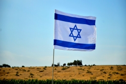 Israeli flag with land in the background