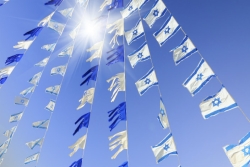 Multiple Israeli flags and blue and white streamers in the sunlight