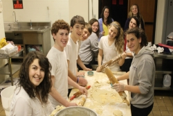 A group of teens making hamantaschen in a synagogue kitchen