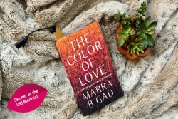 Aerial flatlay of book THE COLOR OF LOVE by Marra Gad sitting on a blanket next to a succulent