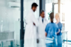 Out of focus image of four medical professionals conferring in a hospital hallway