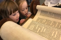 little girls looking at open Torah scroll