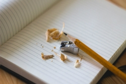 Sharpened pencil sitting on a blank notebook surrounded by pencil shavings