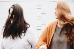 Blurry image of two laughing women with their arms slung around one another