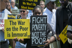 Protesters holding signs including one that says FIGHT POVERTY NOT THE POOR
