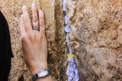 Woman's hand on the Western Wall next to notes in a crevice