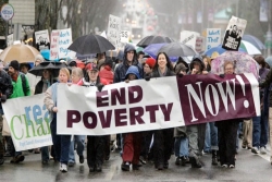 people marching in an anti-poverty rally with a banner 