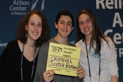 Three teens holding signs in support of criminal justice reform