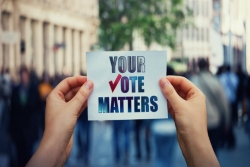 Hands holding up a sign that says YOUR VOTE MATTERS