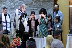 Group of people lighting Shabbat candles at a congregational Shabbat dinner