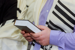 man holding prayerbook and wearing tallit