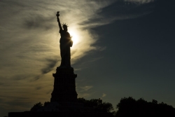 Statue of Liberty in shadow with sun shining behind her