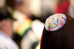 Back view of a long haired woman wearing a brightly colored kippah 