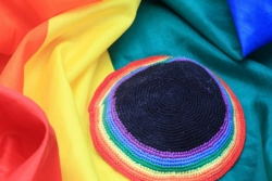 Knitted rainbow kippah resting on a rainbow flag