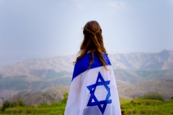 Young woman facing away, wrapped in an Israeli flag