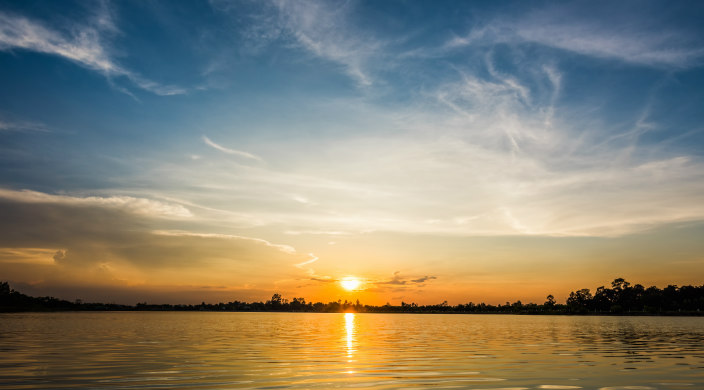 Sunrise over water with trees along the shore